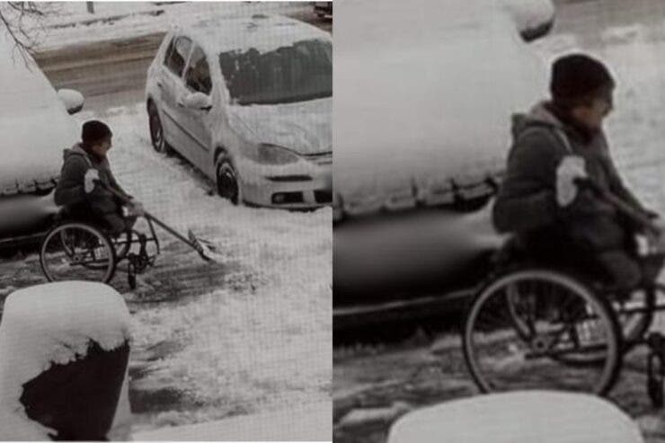 Un bărbat aflat în scaun cu rotile dă zăpada din fața blocului.