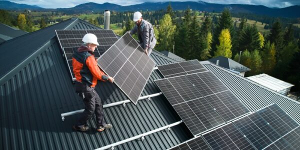 doi tehnicieni instalează panouri fotovoltaice pe acoperișul unei locuințe