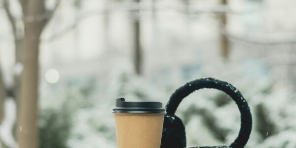 Pahar de cafea la pachet lăsat pe o bancă, într-o dimineață geroasă