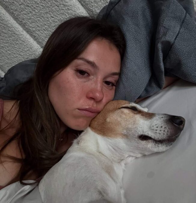 Teodora Stoica, cu ochii în lacrimi, stă întinsă în pat lângă câinele ei Roată în ultimele lui zile