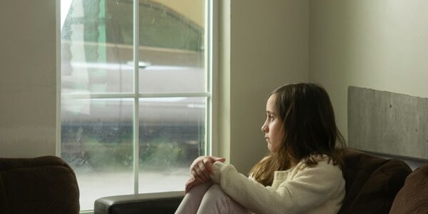Adolescentă tristă, singură pe canapea, privind pe fereastră